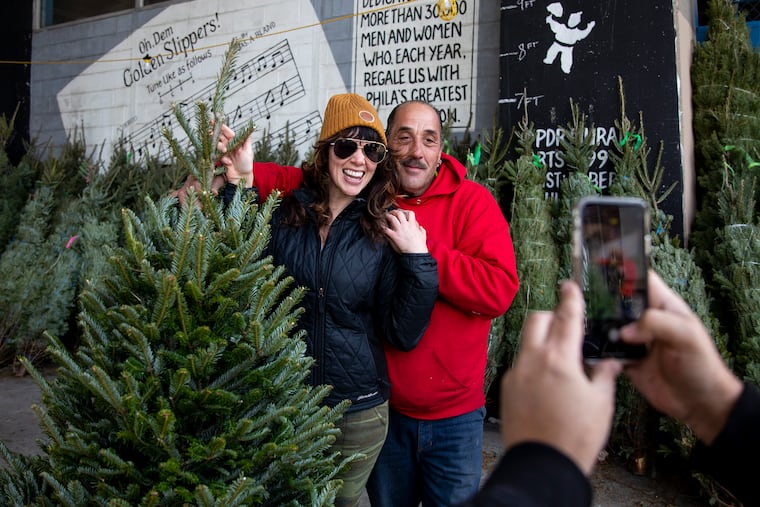 Rocky Yo-Mo of South Philadelphia, owner of Rocky YoMo's Christmas Trees, takes a photo with Britni Volkman of South Philadelphia, with the tree she purchased in 2019.